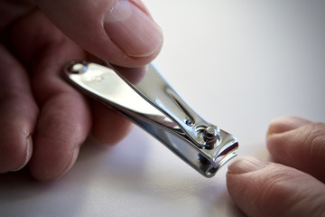 caucasian man using nail clippers on a white background