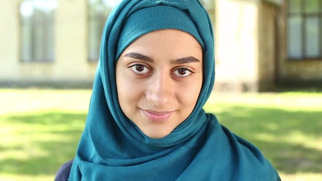 Portrait of a smiling muslim girl in hijab. Close-up face of a happy Arabic young woman with beautiful eyes.