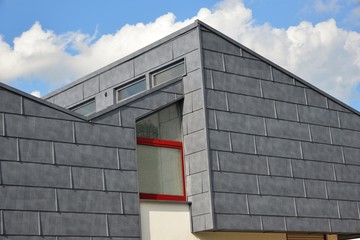 Moderne Wohnhaus-Fassade mit seitlichen Metallschindeln als Wetterschutz