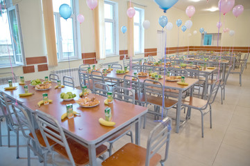kids eating lunch in a social school orphanage,population are orphans,due . Blue and pink balls on the tables. Bananas, apples, cake . Food aid for orphans .
