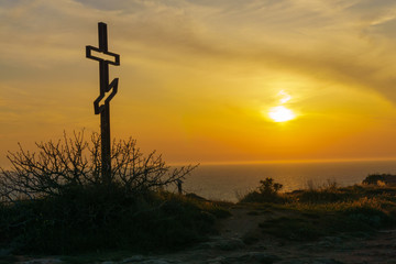 Cross on a cliff with a beautiful sunset sky in the background