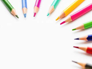 Colorful watercolor pencils on white background. School supplies with round copy space. Kid's stationery. Back to school circle backdrop.