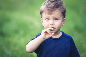 Blond boy in blue t-shirt with beautiful blue eyes looking at something