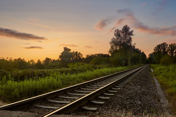 Fototapeta na wymiar Railroad track in countryside during sunset in summer. Transportation concept, travel background.