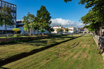 Fototapeta premium River with green grass and old buildings of the city hall of the historical and tourist city of Sao Joao del Rey, in the state of Minas Gerais, Brazil.