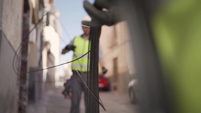Close-up push-in shot of two technicians pulling out a tangled optical fiber cable