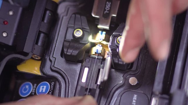 Close up shot of a technician splicing an optical fiber cable in a machine