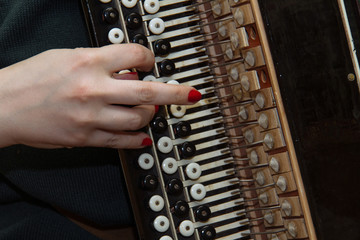 Girl musician plays the the Russian bayan (button accordion) and singing.