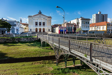 Fototapeta na wymiar River with green grass and old buildings of the city hall of the historical and tourist city of Sao Joao del Rey, in the state of Minas Gerais, Brazil.