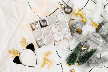 Set of Christmas balls and decorations on white bed with a blanket. Holiday concept. Flat lay, top view