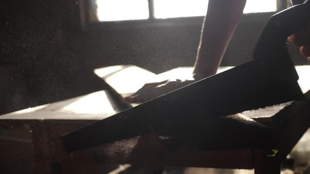 man carpenter handmade and craft concept slow motion video. carpenter sawing a tree in a workshop sawing sunlight from a window silhouette. woodworker lifestyle engaged in processing wood at the