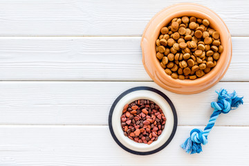 Dog dry food in bowl and toys on white wooden background top view space for text