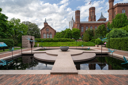 Washington, DC - May 9, 2019: The Moongate Garden with dragonfly statues in the Enid Haupt Garden and the Smithsonian Castle on the National Mall