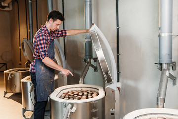 Caucasian man opening oven for firing ceramics pots.