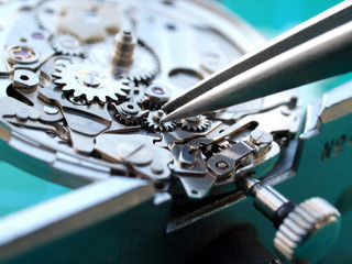 close up of watchmaker repairing old watch meachism, taking small gear with tweezers
