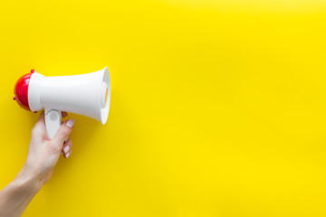Announcement with megaphone in hand on yellow background top view mockup