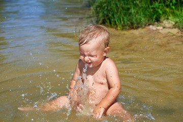 Fototapeta na wymiar Toddler splashing water near the shore