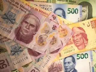 Mexican peso bills spread randomly over a flat surface