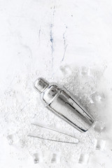 Pile of ice cubes and shaker on marble bar desk background top view space for text