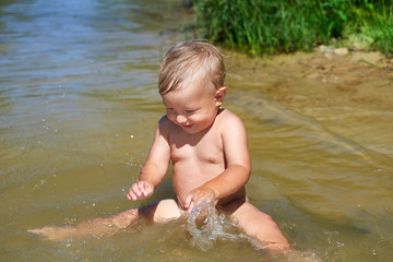 Baby boy plays in the water near the shore