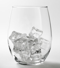 An empty wine glass with some ice cubes inside.