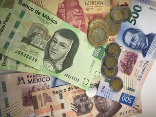 Fototapeta na wymiar Mexican peso bills spread randomly over a flat surface
