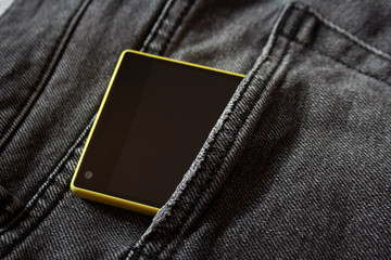Modern yellow smartphone in grey jeans pocket close up