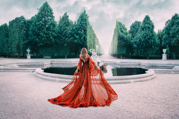 A mysterious blond woman walks in a luxurious, royal garden. The view from the back. Princess in a...