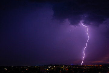 Naklejka na ściany i meble Lightning strikes storm over city purple light.