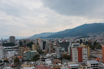 Obraz premium Atardecer de ciudad sudamerica en Quito Ecuador con edificios y montañas de fondo con cielo nublado