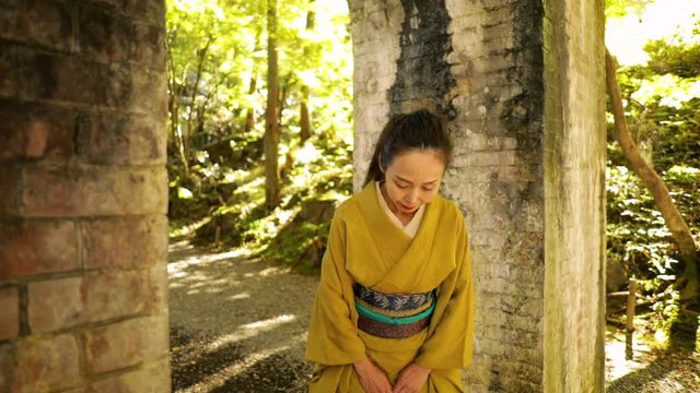 Elegant Japanese woman enjoying a park in Kyoto Japan. Bows towards the camera.