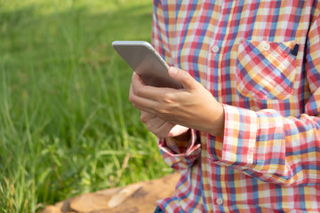 Woman hand holding and using smart phone with blank screen in the park