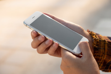 Woman hand holding and using smart phone with blank screen at outdoor background