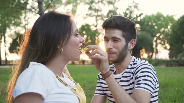 pregnant woman and her boyfriend on picnic and eating grapes