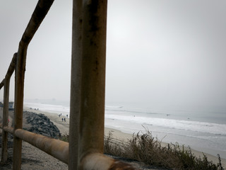 Beach through railings on a misty day