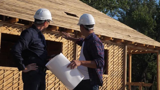 teamwork. concept building constructing architect slow motion video. two men builder in helmets study the house plan. two architects working on the construction of a frame house business contrast at