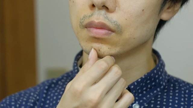 無精ひげを触る日本人男性