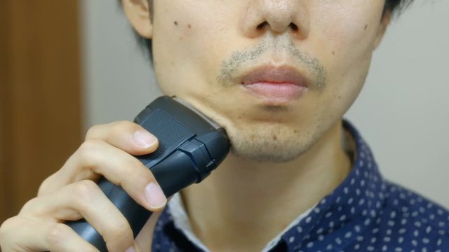 電気シェーバーでひげを剃る日本人男性