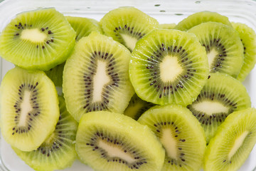 Many kiwi slices are placed in a glass crisper. Kiwifruit slices without peel.