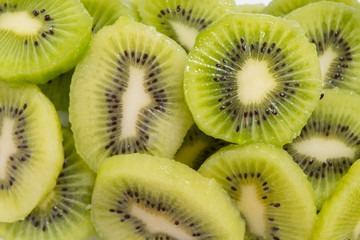 Many kiwi slices are placed in a glass crisper. Kiwifruit slices without peel.