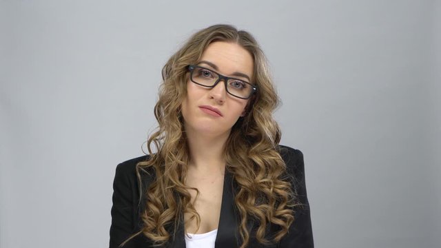 Bussines woman in glasses stands in expectation at grey background