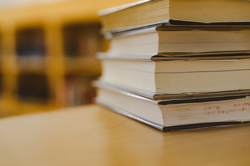 Book in library with old open textbook, stack piles of literature text archive on reading desk, and aisle of bookshelves in school study class room background for academic education learning concept