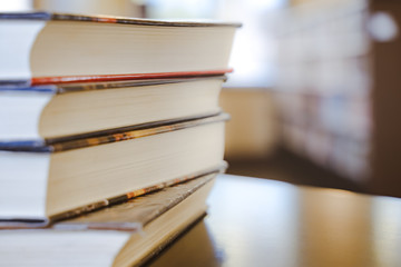 Book in library with old open textbook, stack piles of literature text archive on reading desk, and aisle of bookshelves in school study class room background for academic education learning concept