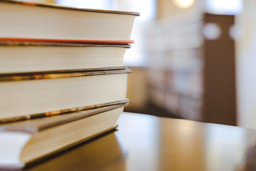 Book in library with old open textbook, stack piles of literature text archive on reading desk, and aisle of bookshelves in school study class room background for academic education learning concept