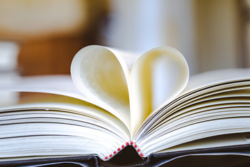 Close-up, The book on the ground is open pages are forming hart a symbol of love.Book in library with old open textbook, stack piles of literature text archive on reading desk, 