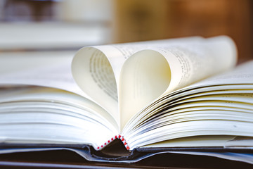 Close-up, The book on the ground is open pages are forming hart a symbol of love.Book in library with old open textbook, stack piles of literature text archive on reading desk, 