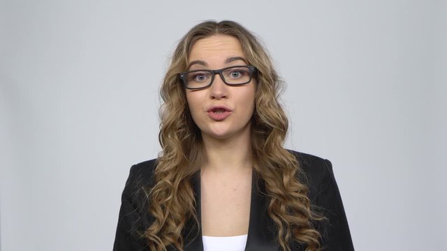 Businesswoman is reporting and tells a lot of interesting news against grey background