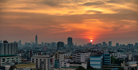 Obraz premium Bangkok city with a beautiful sunset over the skyline with orange skies, buildings and clouds.