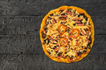 Large round homemade pizza on a wooden table. The view from the top.