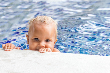 Fototapeta na wymiar Cute baby swims in a swimming pool in summer